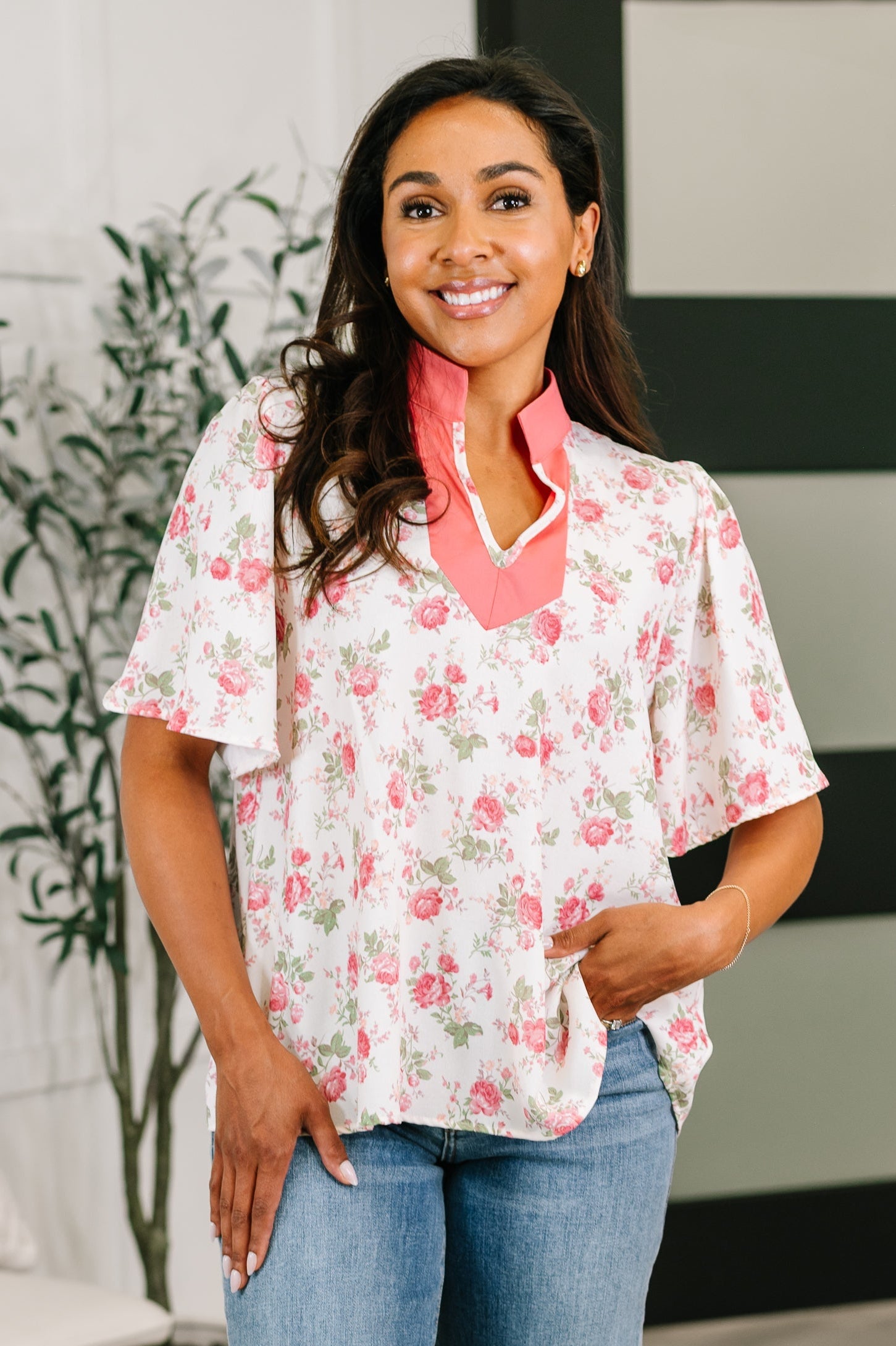 Woman wearing a floral blouse with a pink collar in an indoor setting
