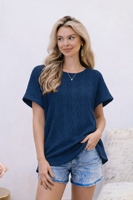 Woman wearing a navy blue oversized t-shirt and denim shorts against a white background