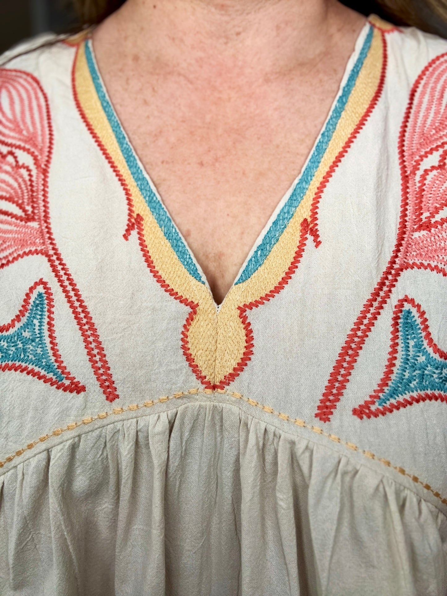 Close-up of a dress with colorful embroidery on a neutral background