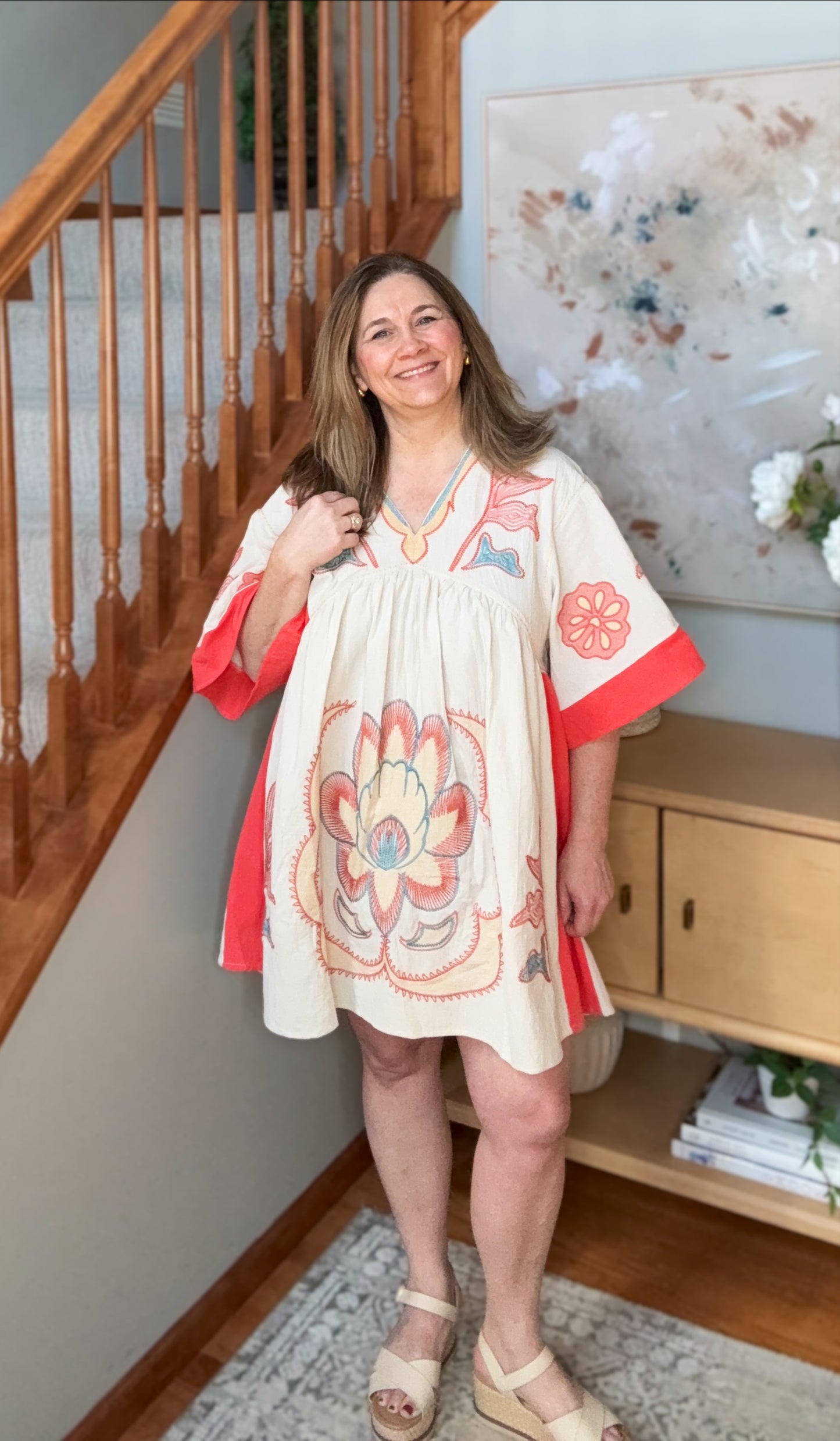 Woman wearing a floral dress with red accents in a home setting