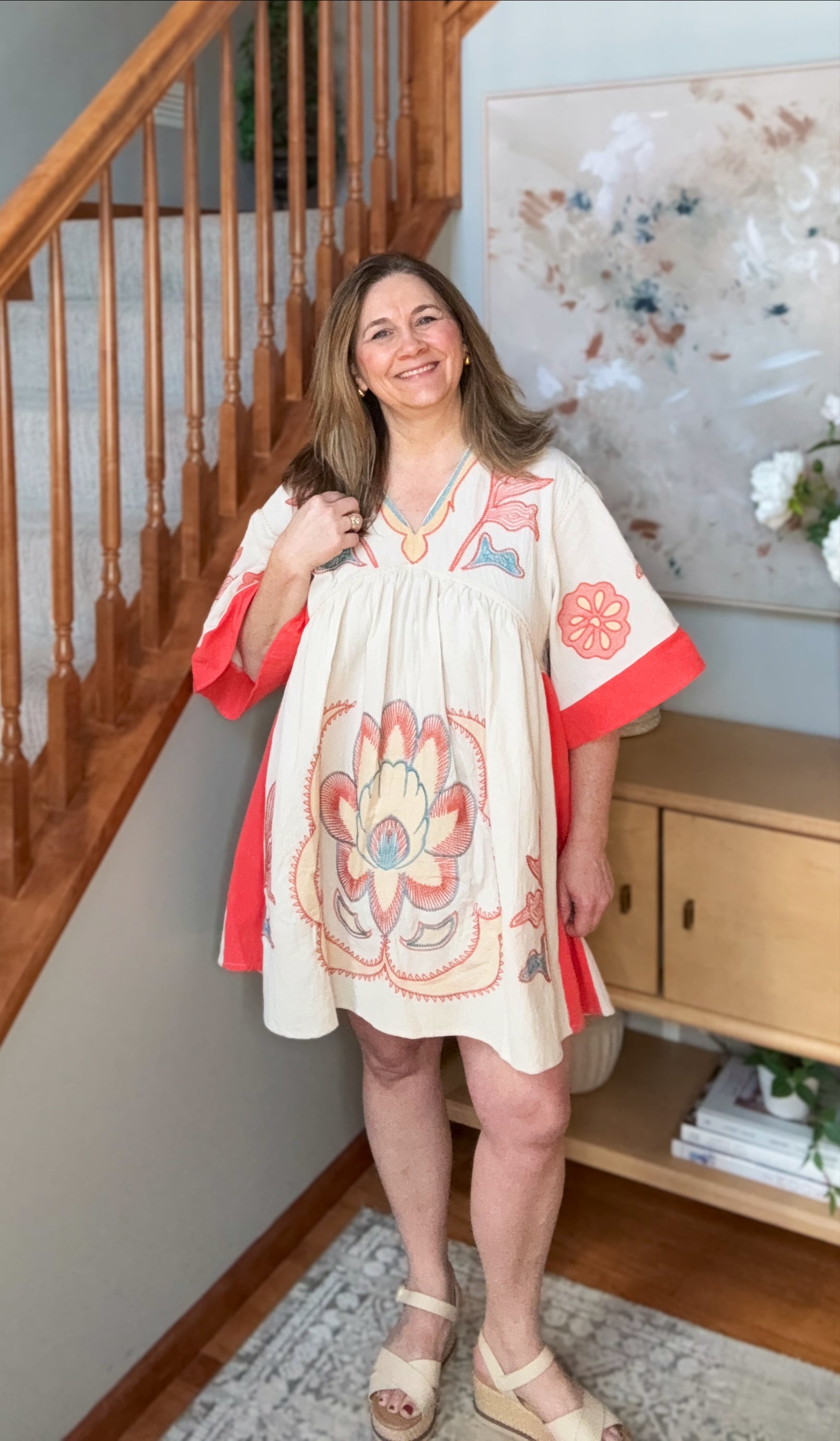 Woman wearing a floral dress with red accents in a home setting