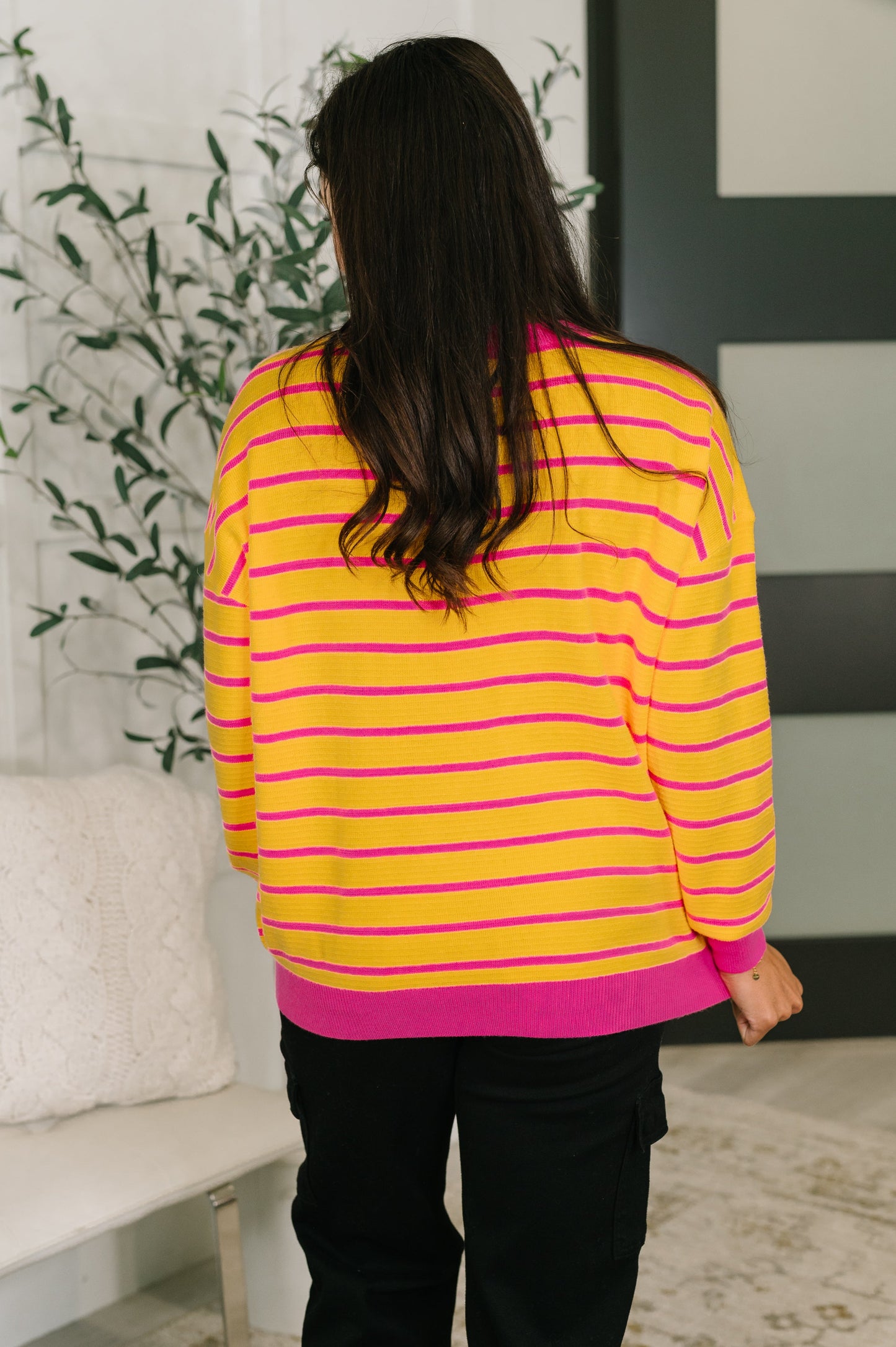 Person wearing a yellow and pink striped sweater in an indoor setting