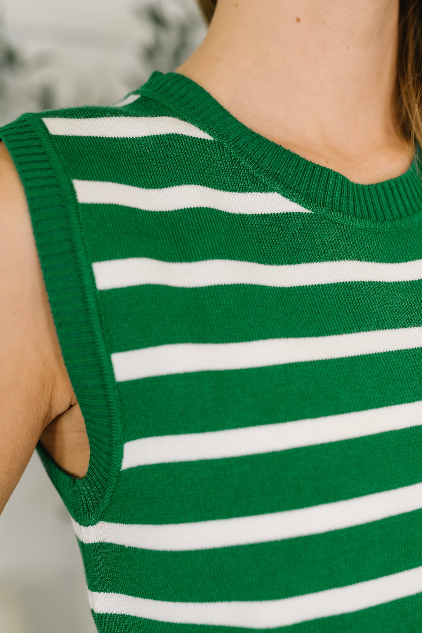 Green and white striped sleeveless top worn by a person