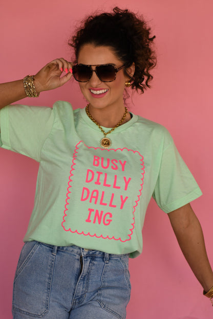 Woman wearing a light green t-shirt with pink text against a pink background