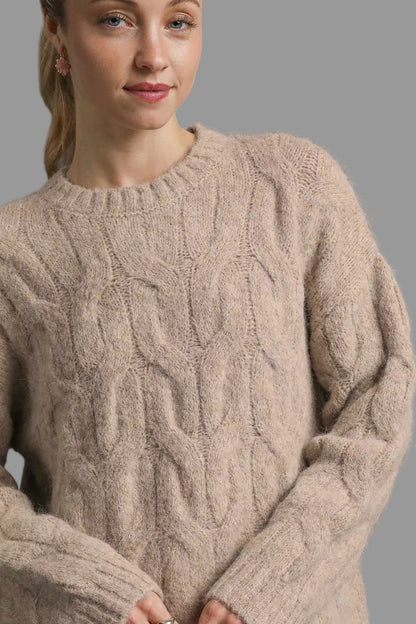 Woman wearing a beige cable knit sweater against a gray background