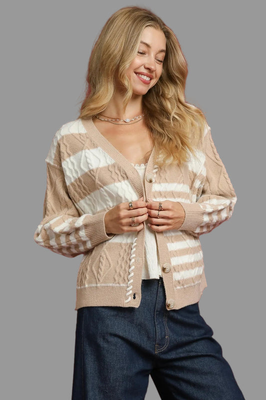 Woman wearing a beige and white striped cardigan on a gray background