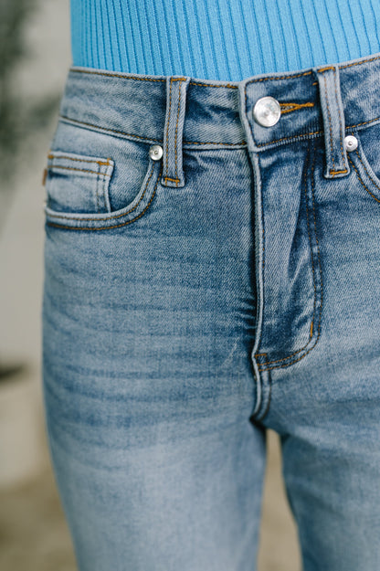 Close-up of a person wearing light blue denim jeans with a bright blue ribbed top visible at the waistband.