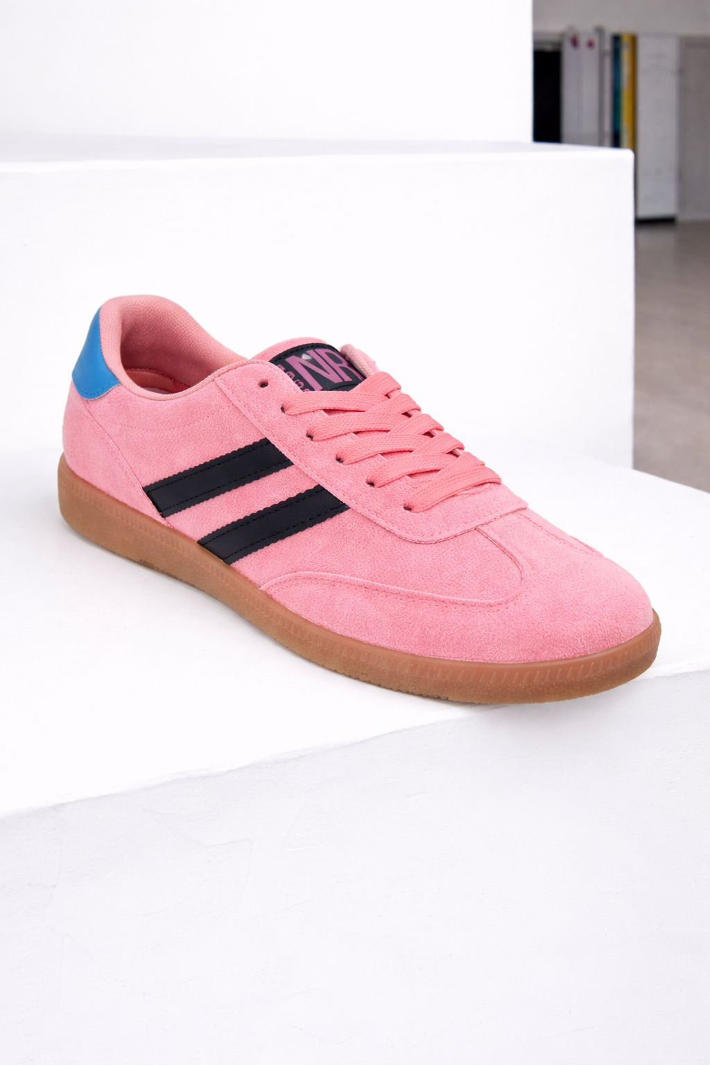 Pink sneaker with black stripes and blue accents on a white surface
