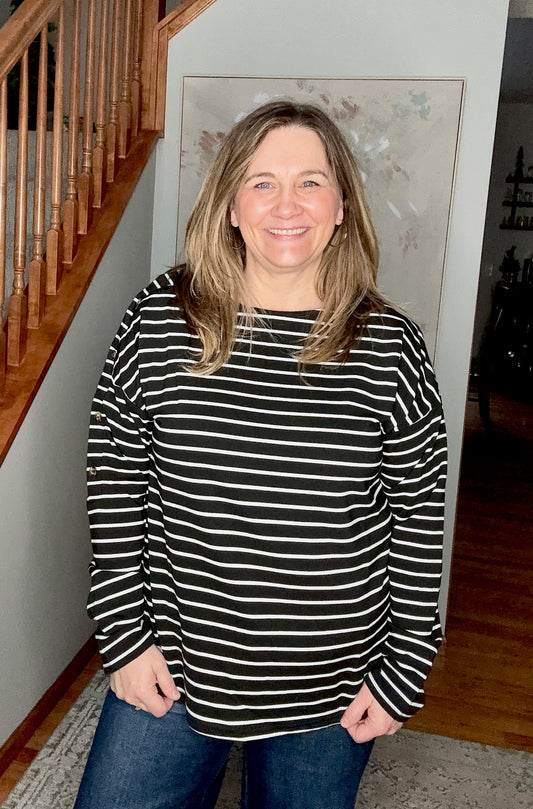Woman wearing a black and white striped sweater standing in a home setting.
