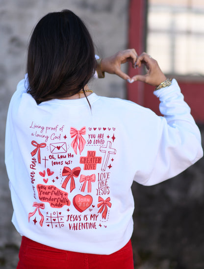 Person wearing a white sweatshirt with red graphics and text, standing against a blurred background.