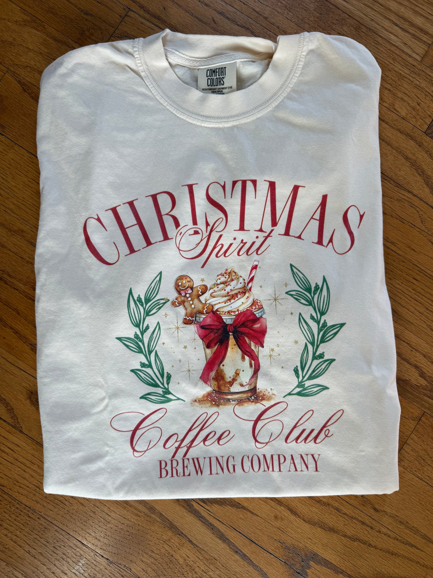 Folded white t-shirt with Christmas-themed design on a wooden surface