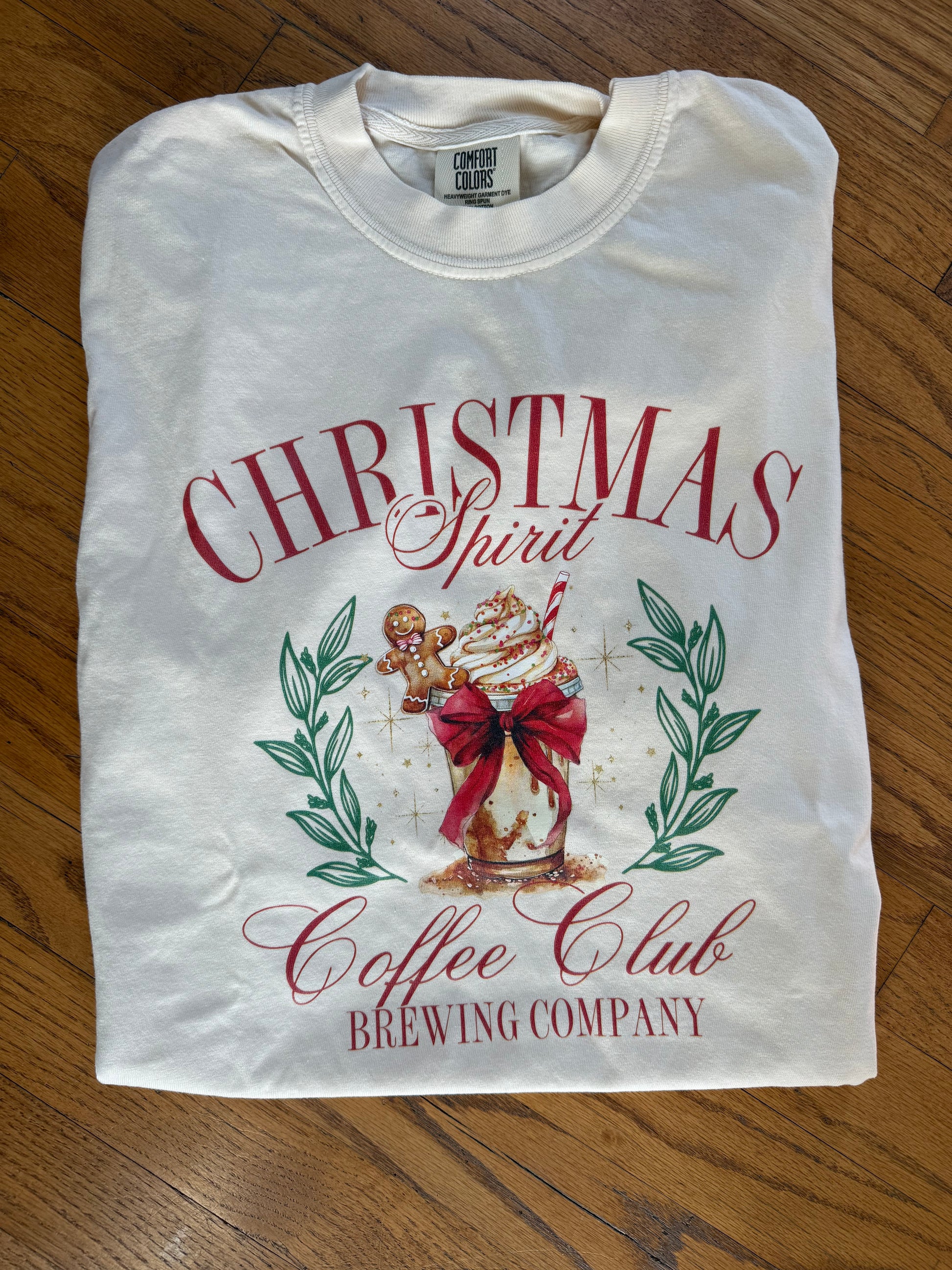 Folded white t-shirt with Christmas-themed design on a wooden surface