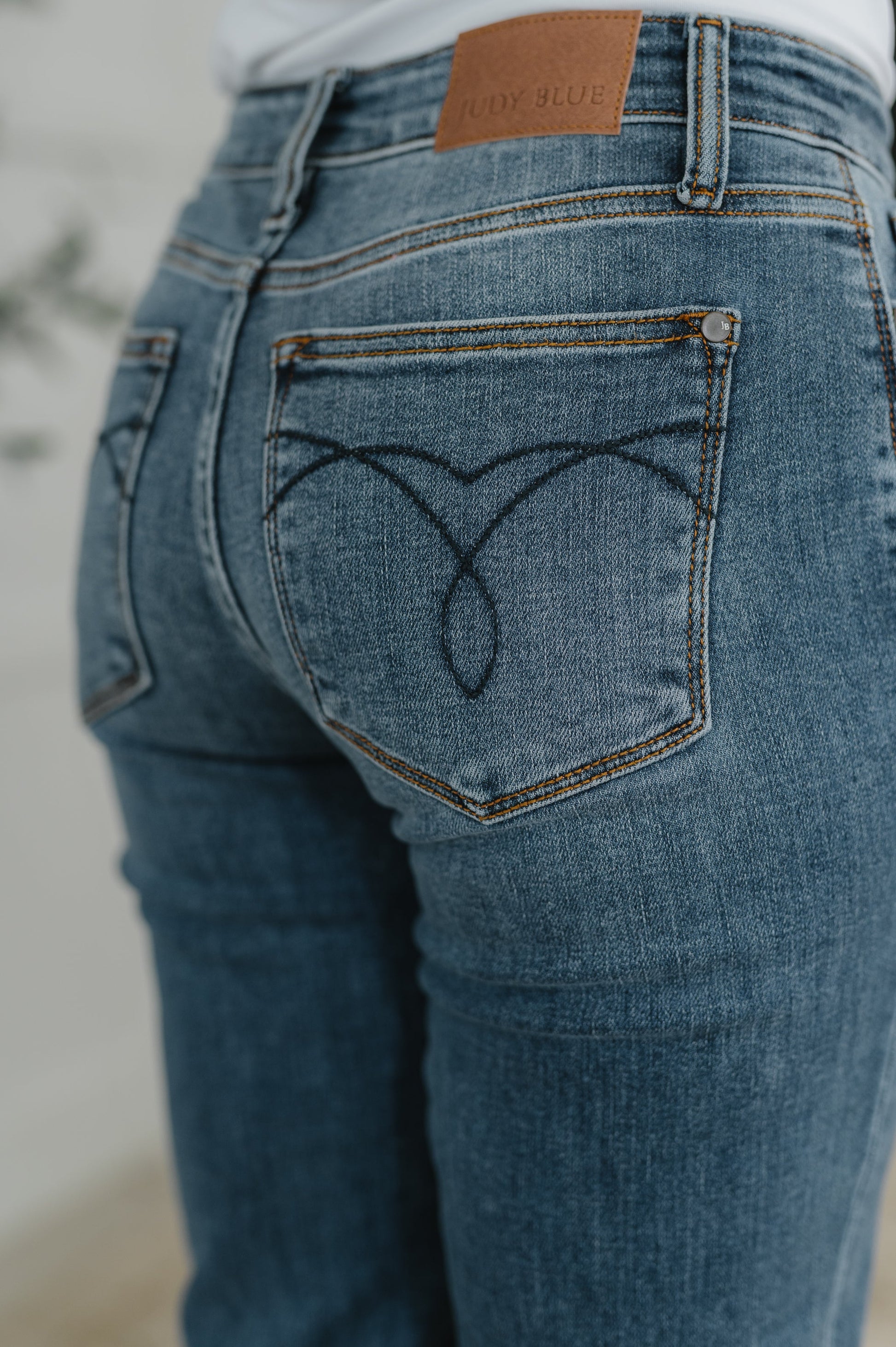 Close-up of blue jeans with a heart design on the pocket and a brand tag.