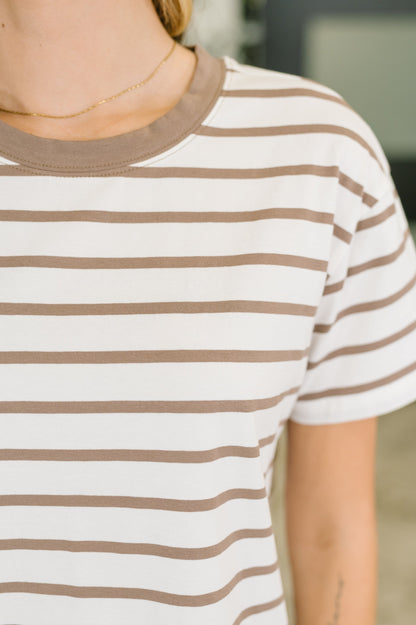 A close-up of a person wearing a short-sleeve crewneck t-shirt with horizontal brown and white stripes.