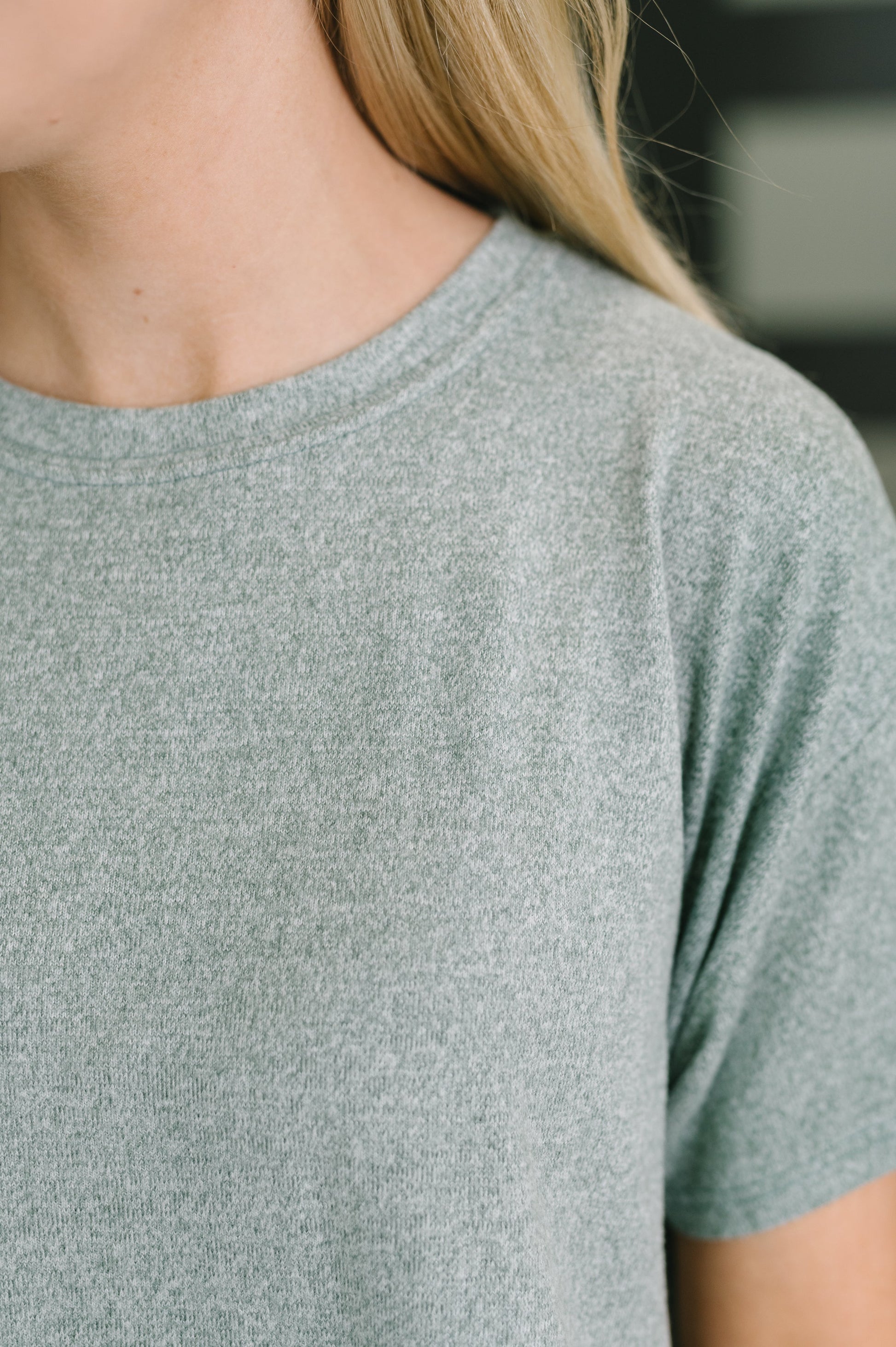 Close-up of a person wearing a short-sleeve crew-neck t-shirt in heather gray.