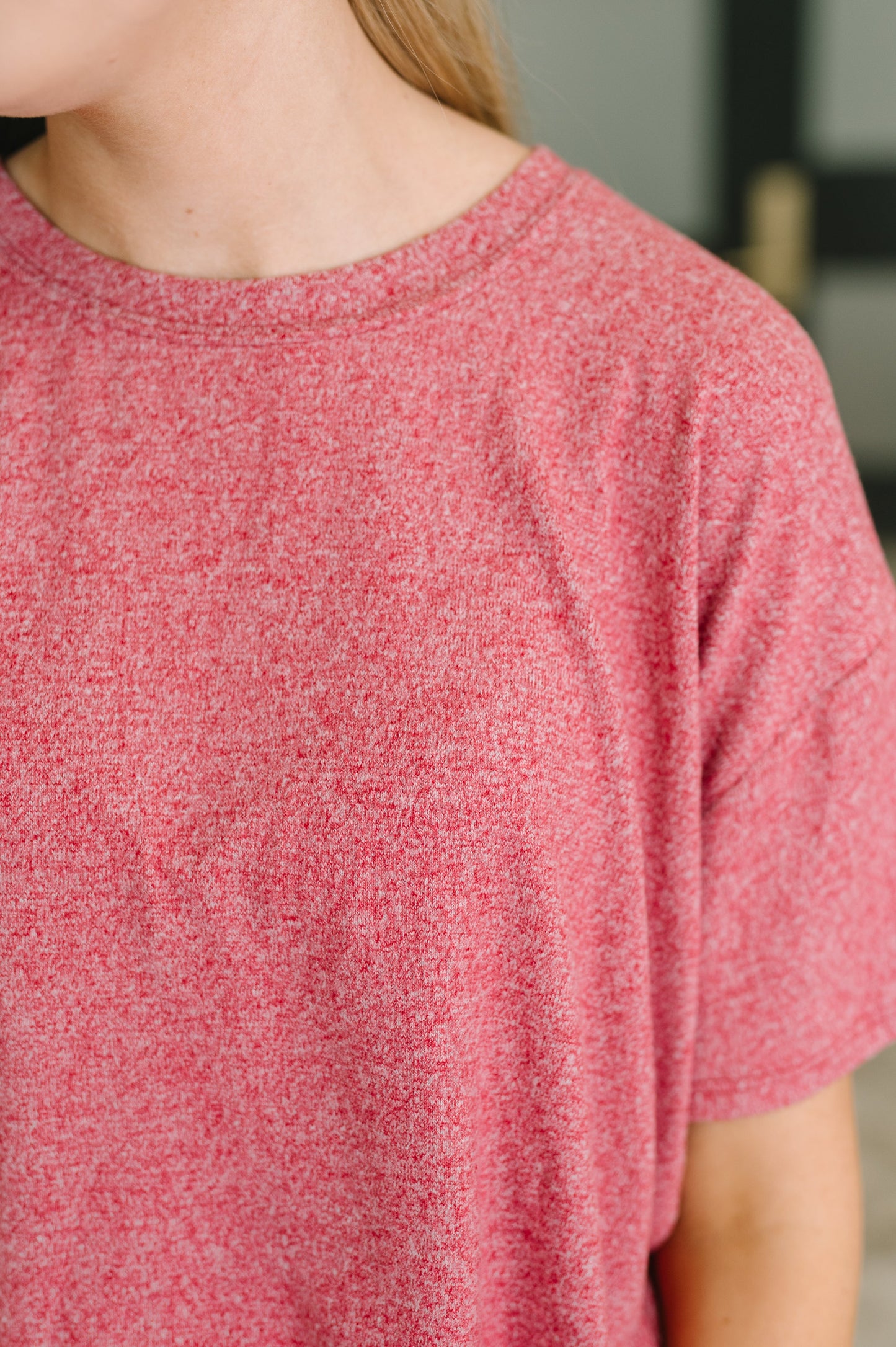 Close-up of a person wearing a heathered pink short-sleeve crewneck t-shirt.