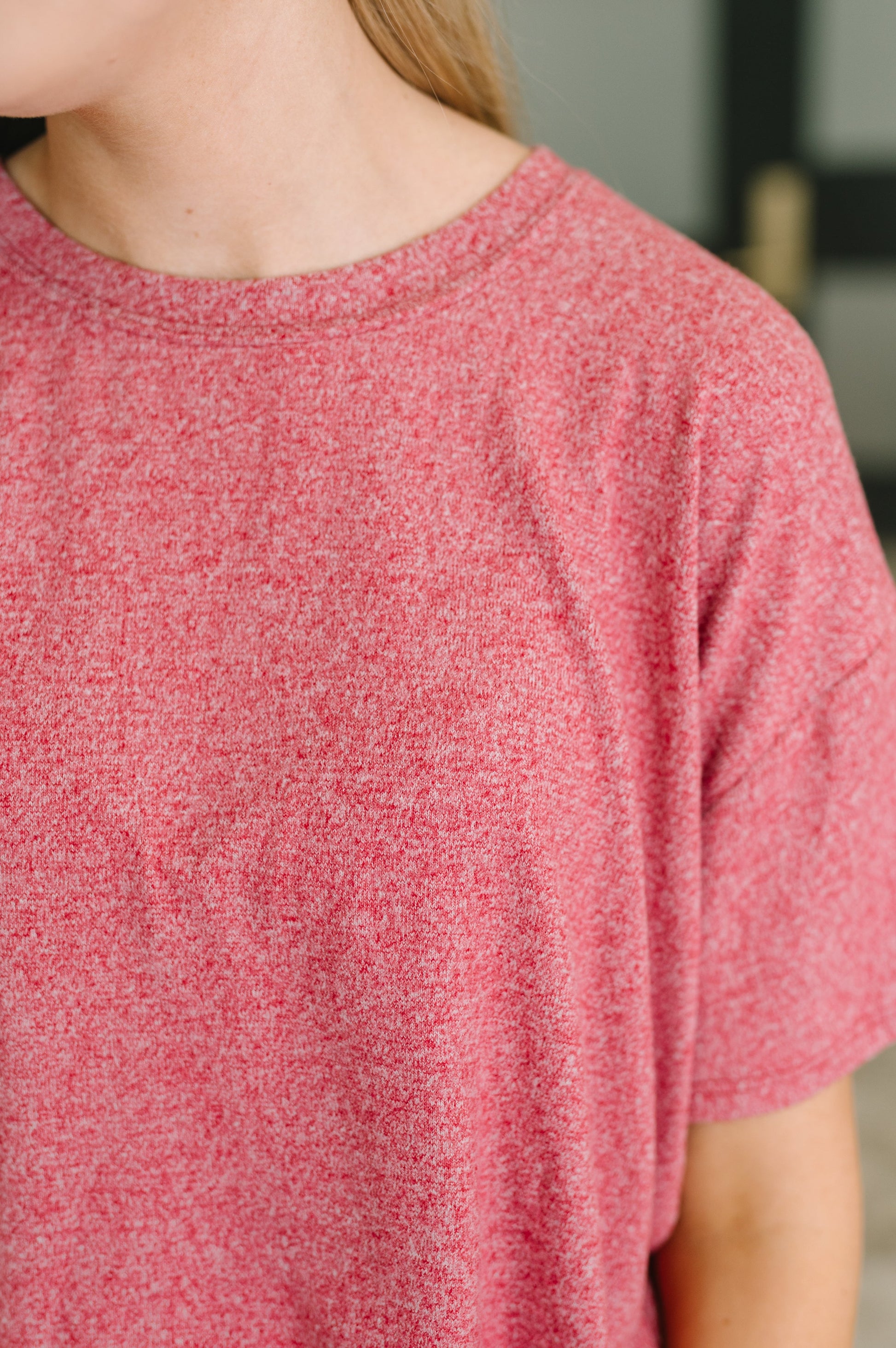 Close-up of a person wearing a heathered pink short-sleeve crewneck t-shirt.