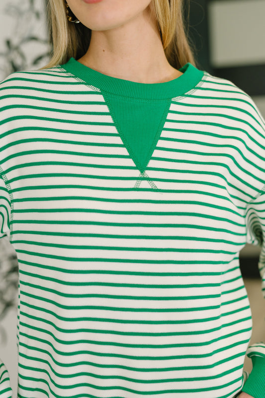 Green and white striped shirt with a brand logo on a blurred background