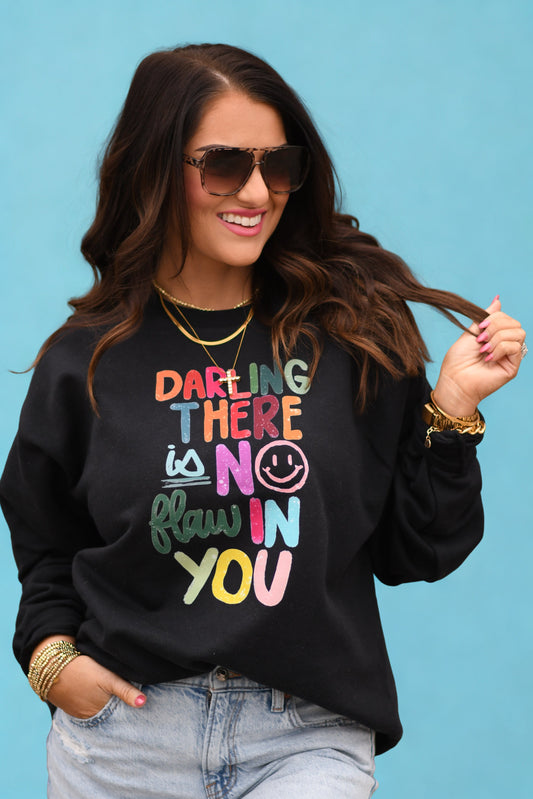 Woman wearing a black sweatshirt with colorful text on a blue background