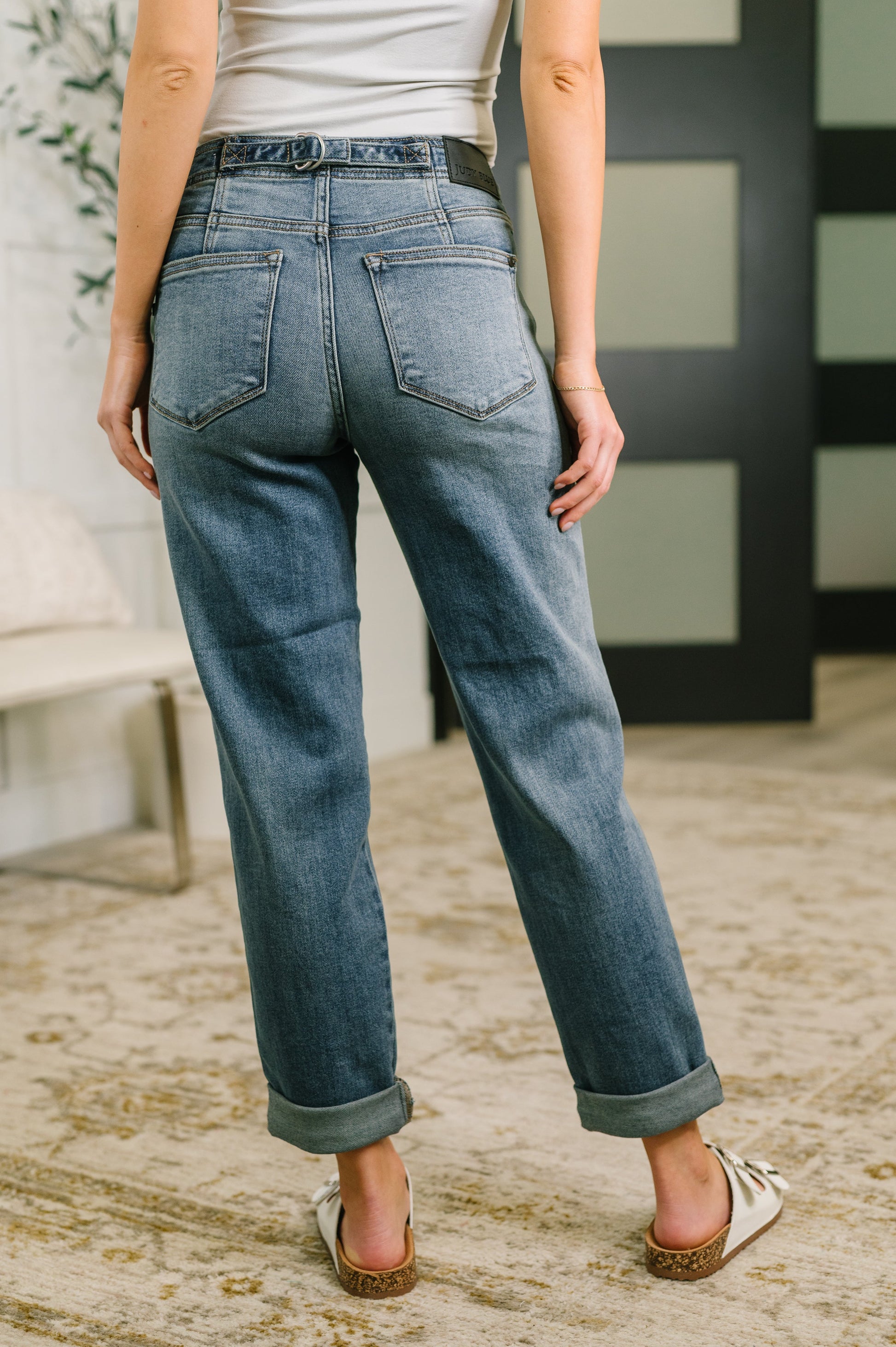 Person wearing blue jeans standing on a textured floor with a blurred background