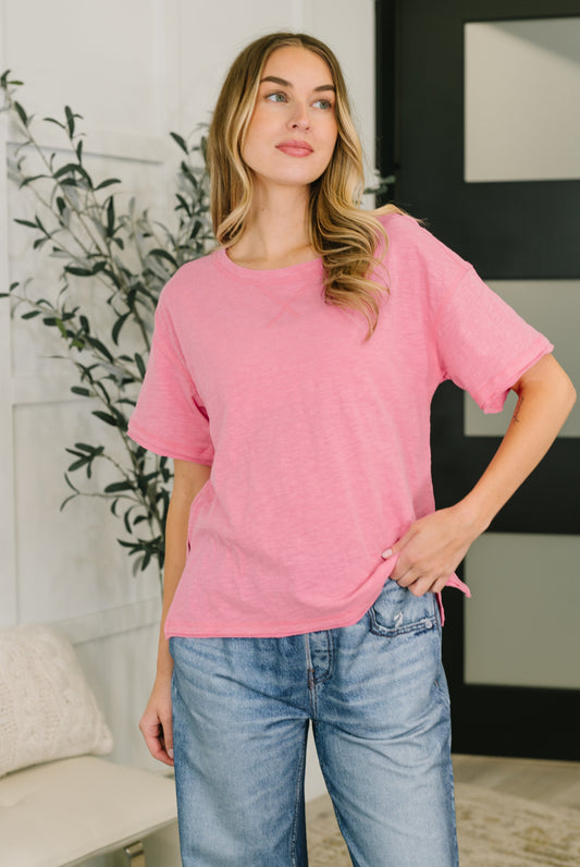 Woman wearing a pink oversized shirt and blue jeans indoors.