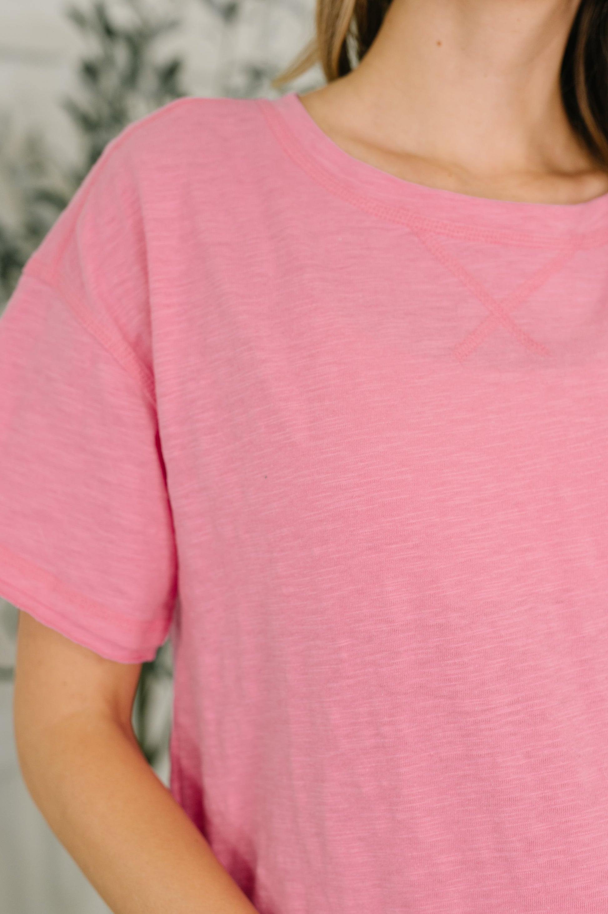 Close-up of a person wearing a pink textured shirt with a blurred background
