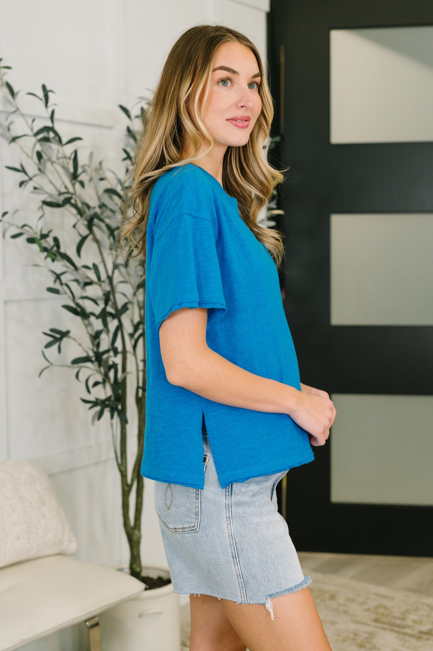 Woman wearing a blue top and denim skirt in an indoor setting