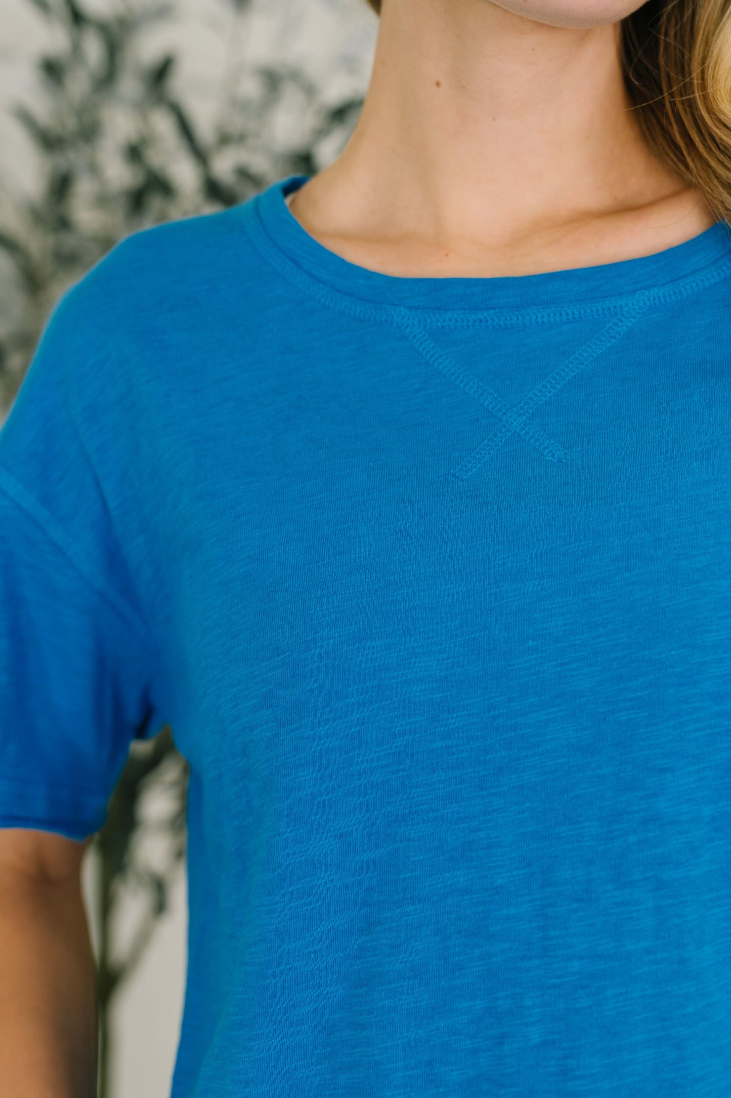Close-up of a person wearing a blue t-shirt with a blurred background