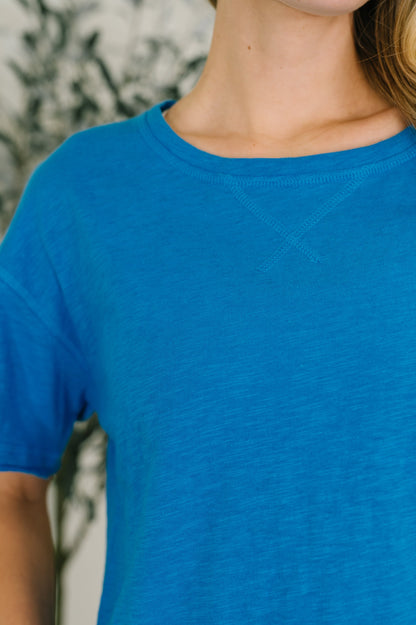 Close-up of a person wearing a blue t-shirt with a blurred background
