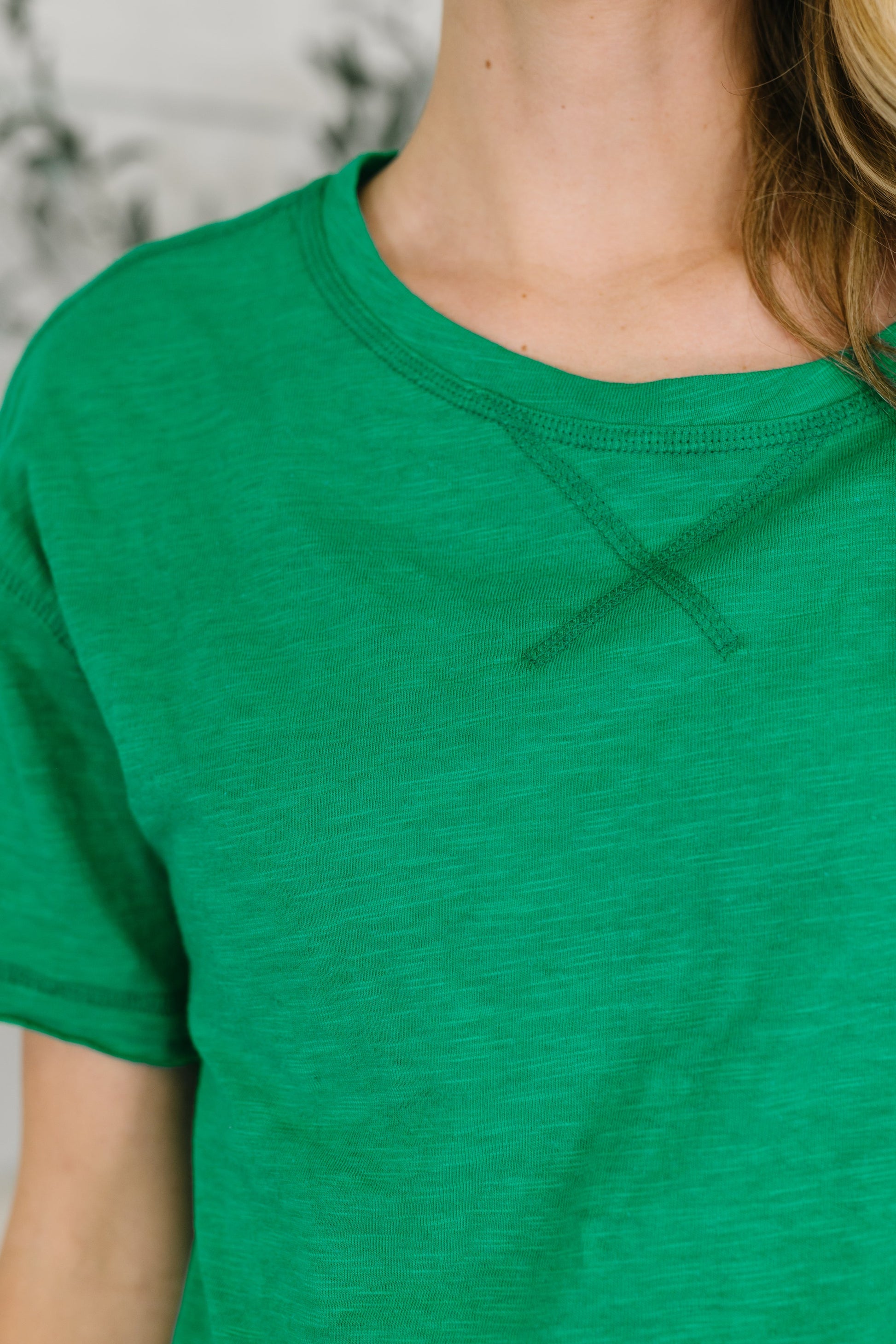 Green t-shirt worn by a person with a blurred background