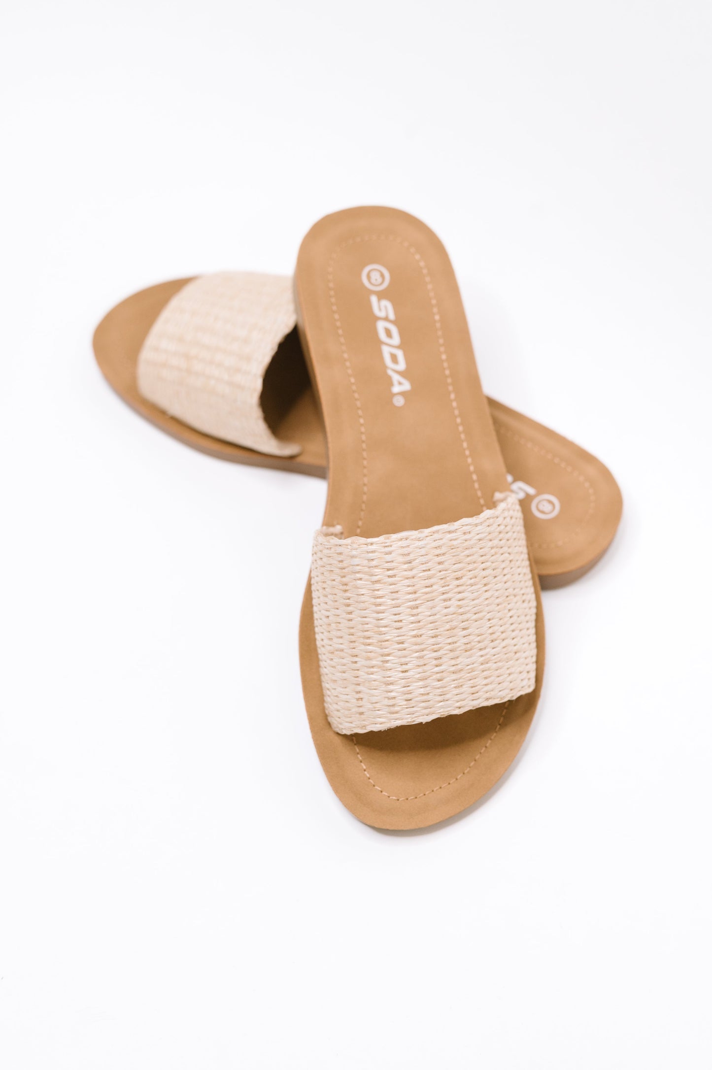 A pair of SODA slide sandals with a tan footbed and a beige woven strap, shown on a clean white background.