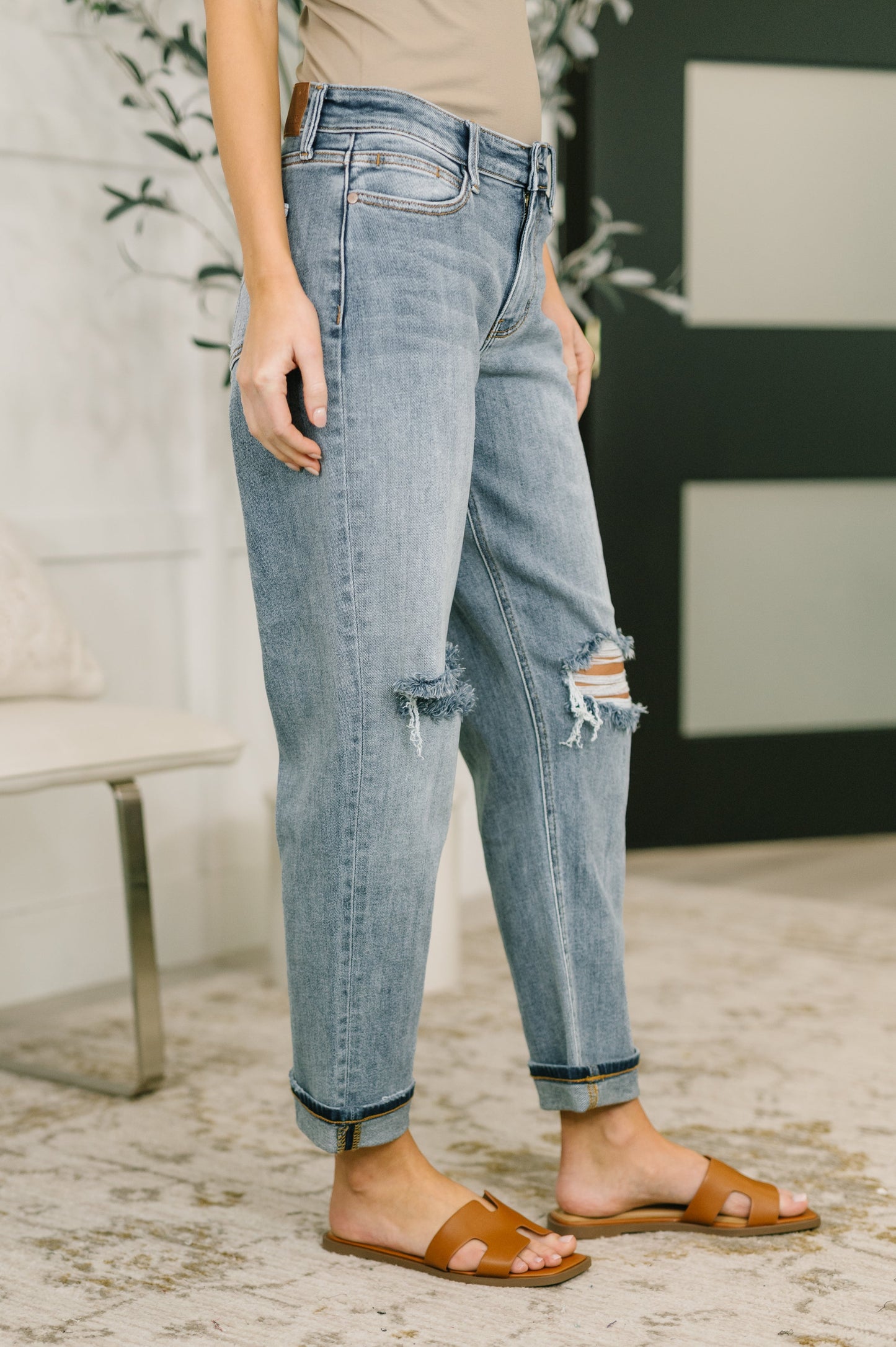 Person wearing light blue jeans with slight distressing, standing indoors.