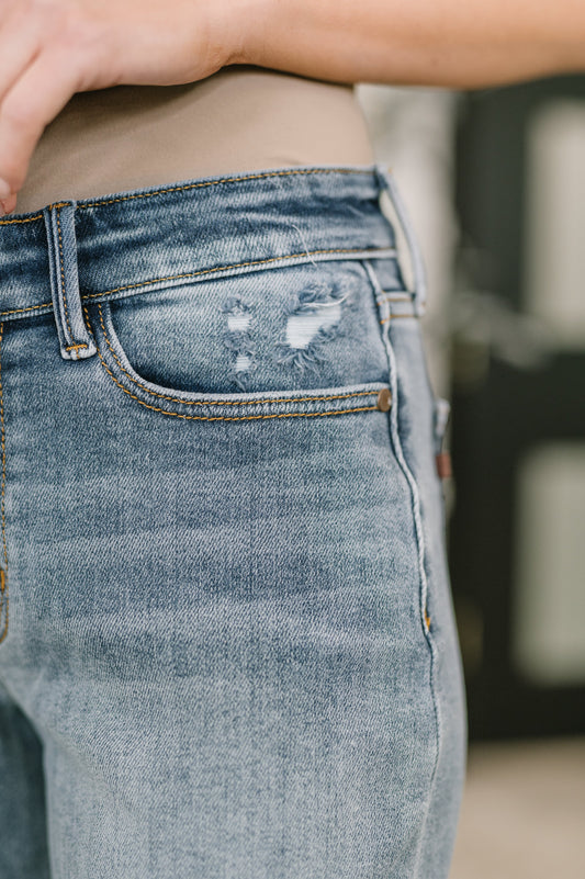 Close-up of a person wearing distressed blue jeans with a blurred background