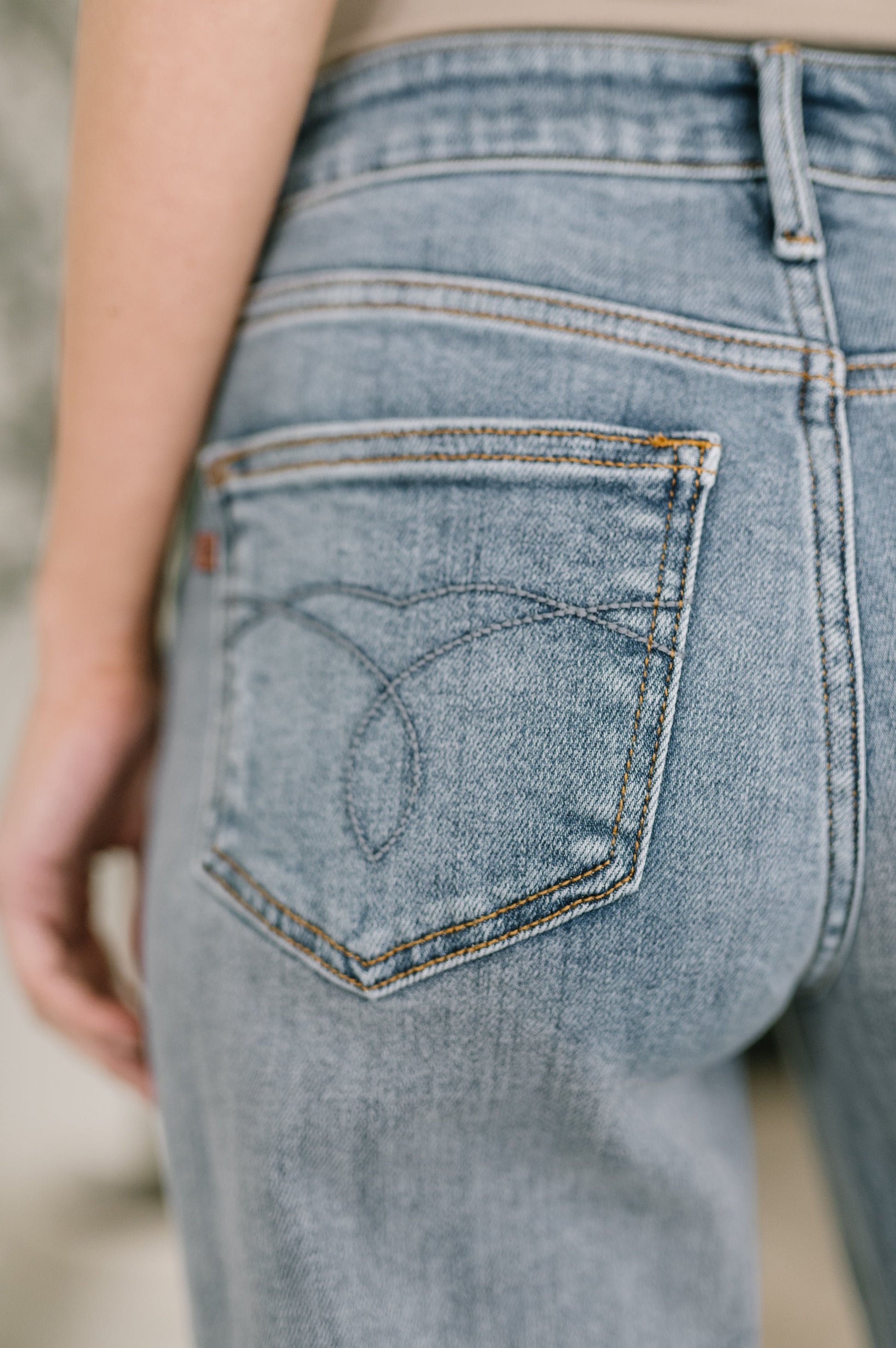 Close-up of a person wearing light blue jeans with a focus on the back pocket.