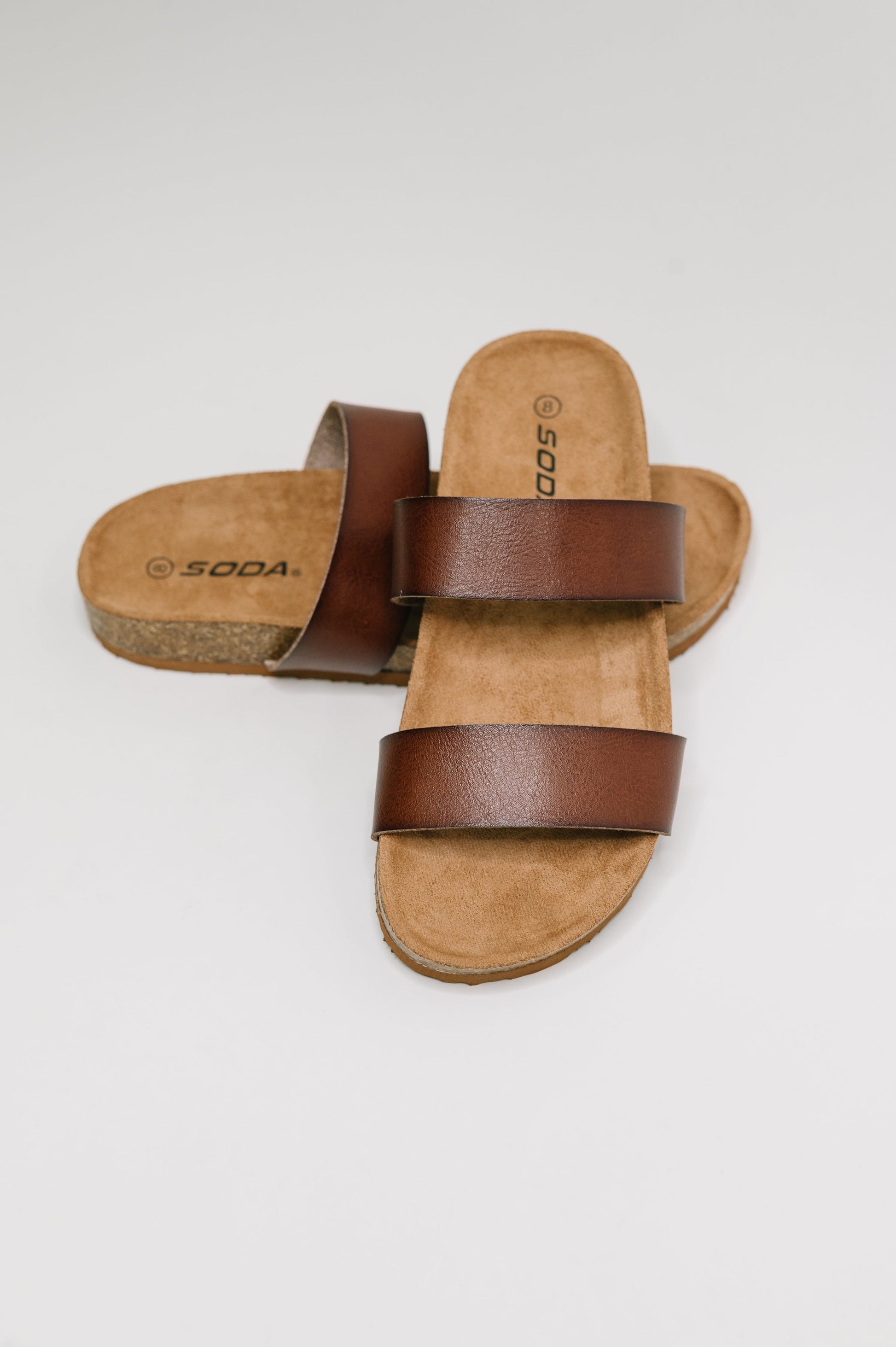 Pair of brown sandals with leather straps on a white background