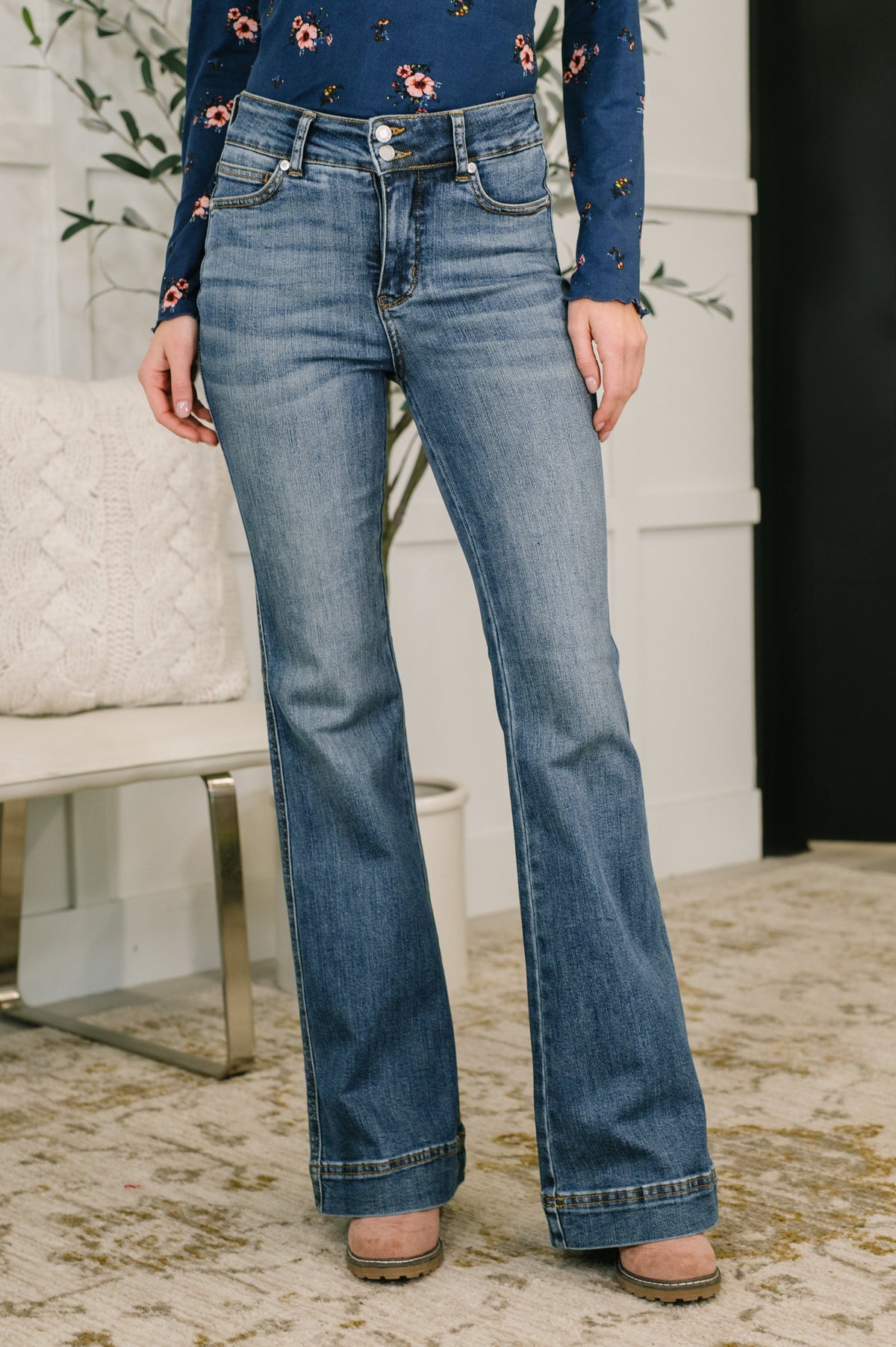 Person wearing blue jeans with a floral top in an indoor setting