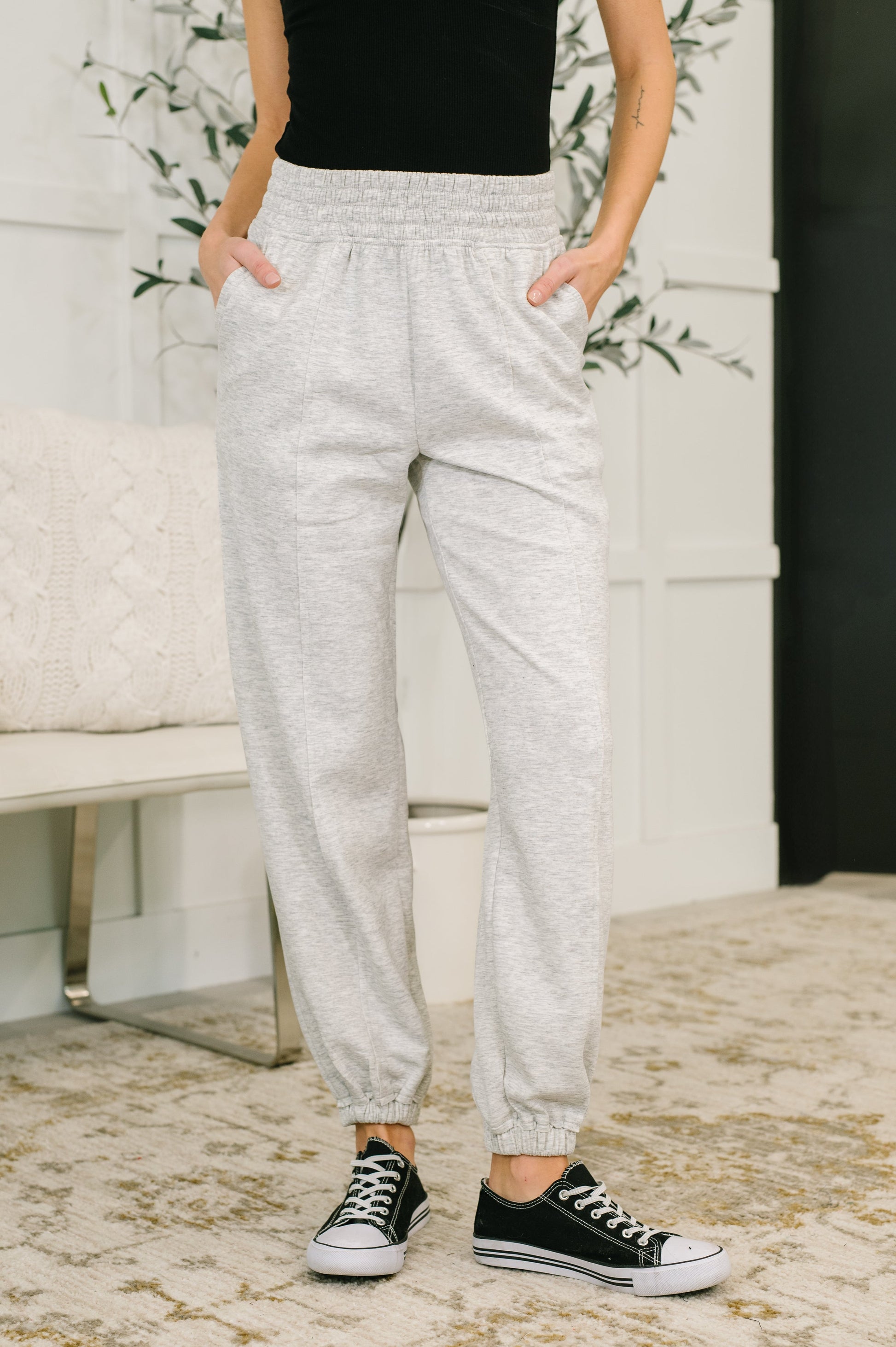 Person wearing gray sweatpants and black sneakers in a home setting