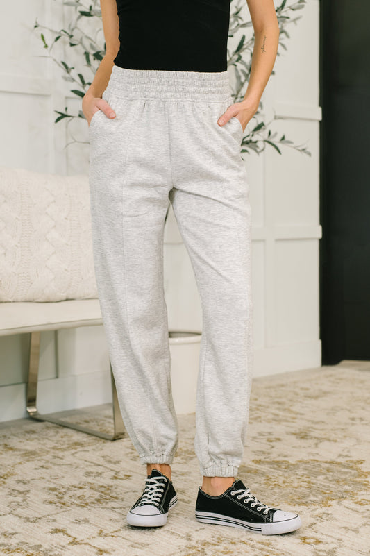 Person wearing gray sweatpants and black sneakers in a home setting