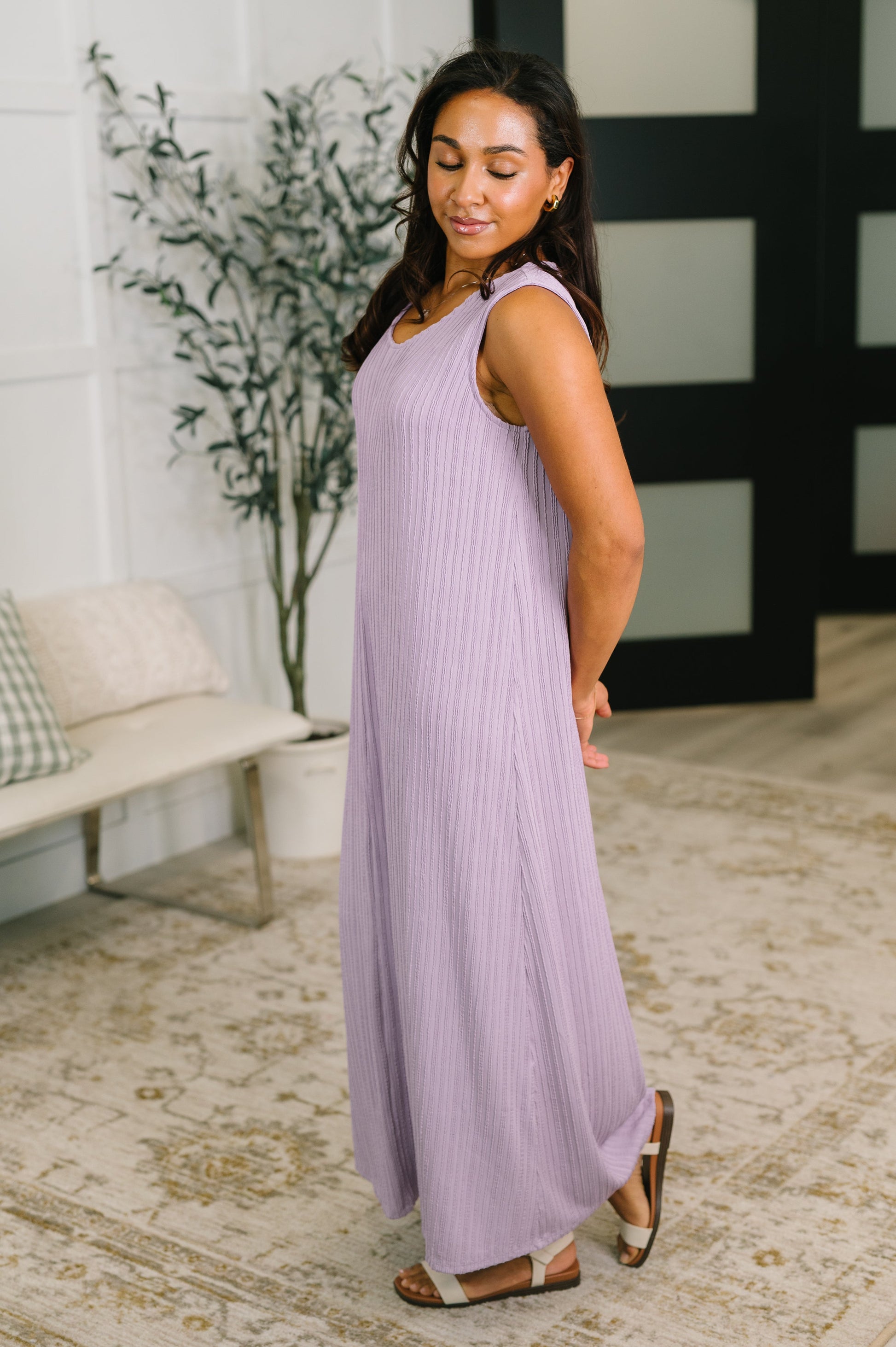 Woman wearing a light purple sleeveless dress in a home setting.