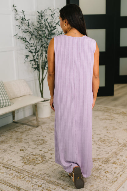 Woman wearing a long, light purple dress in a home setting.