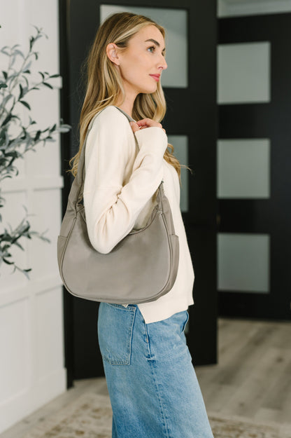 Woman holding a gray shoulder bag in an indoor setting