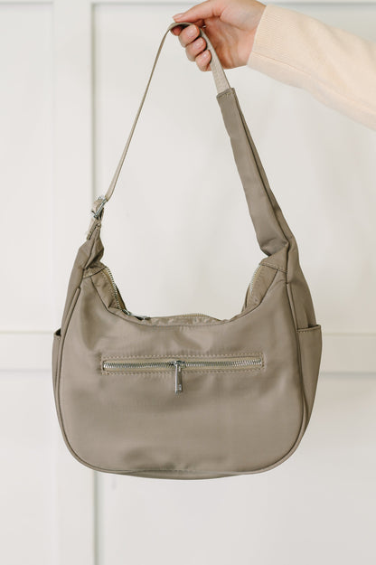 Beige handbag held by a hand against a light background