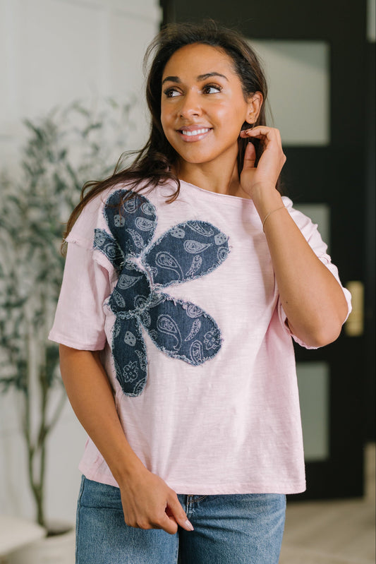 Woman wearing a pink t-shirt with a blue cactus design, standing indoors.
