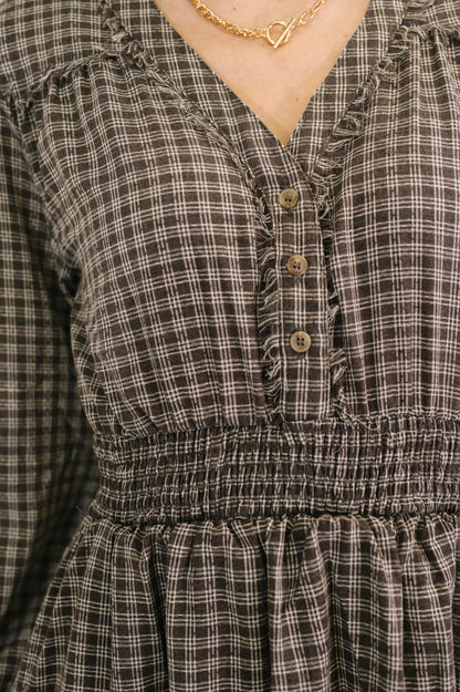 Plaid dress with button details and a gold necklace.