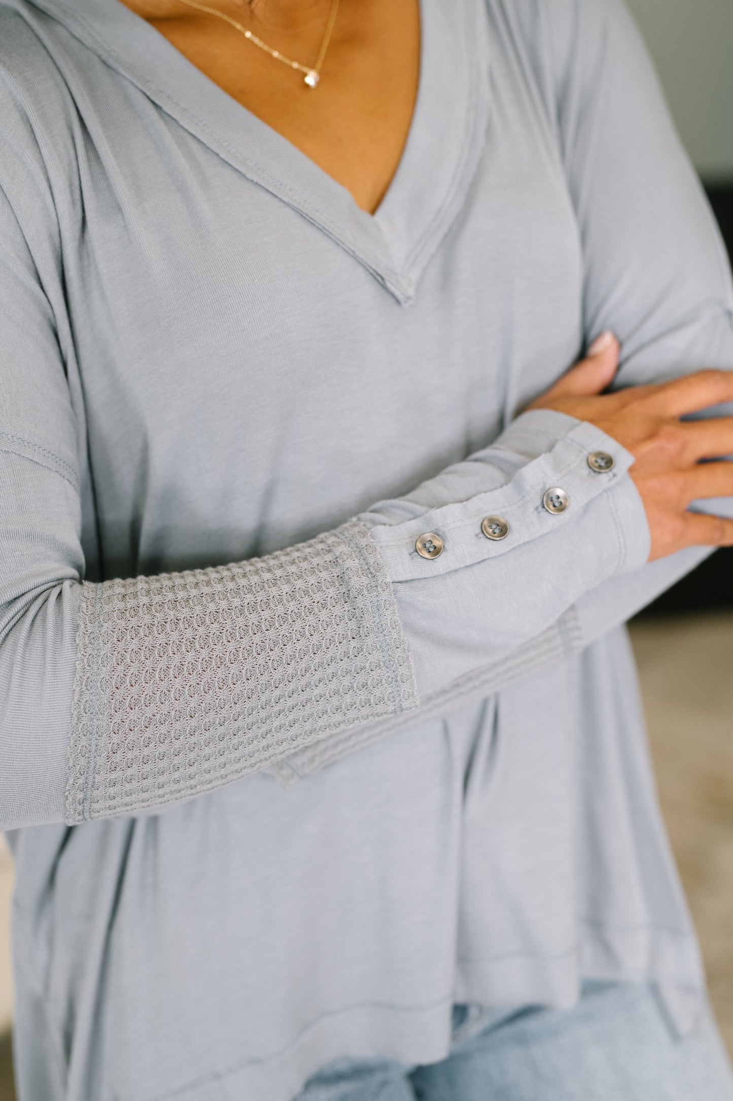 Gray long-sleeve top with textured cuffs and button details