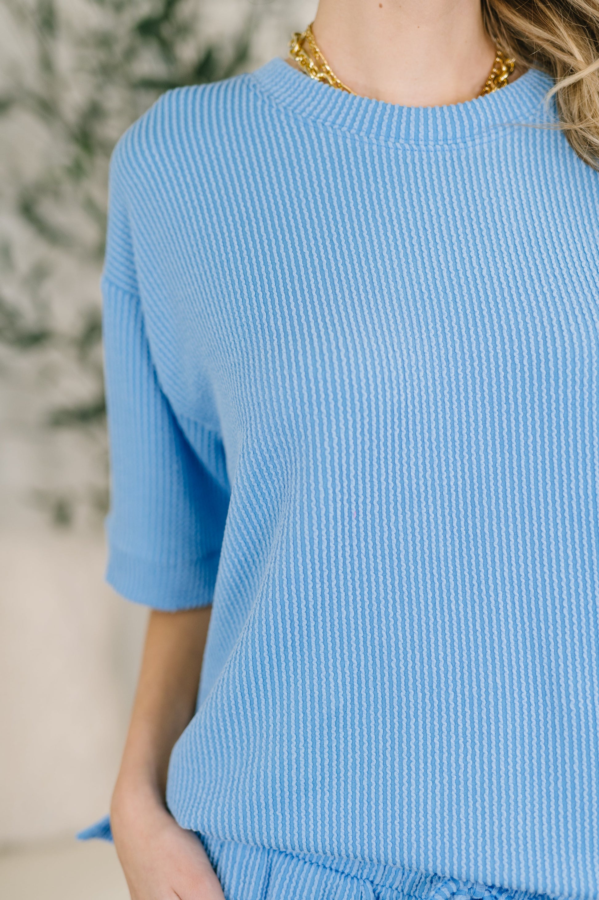Person wearing a blue ribbed sweater with a blurred background