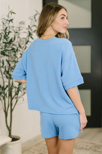 Woman wearing a light blue outfit with a plant and door in the background