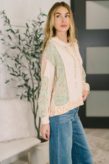 Woman wearing a floral blouse and jeans indoors with a plant in the background