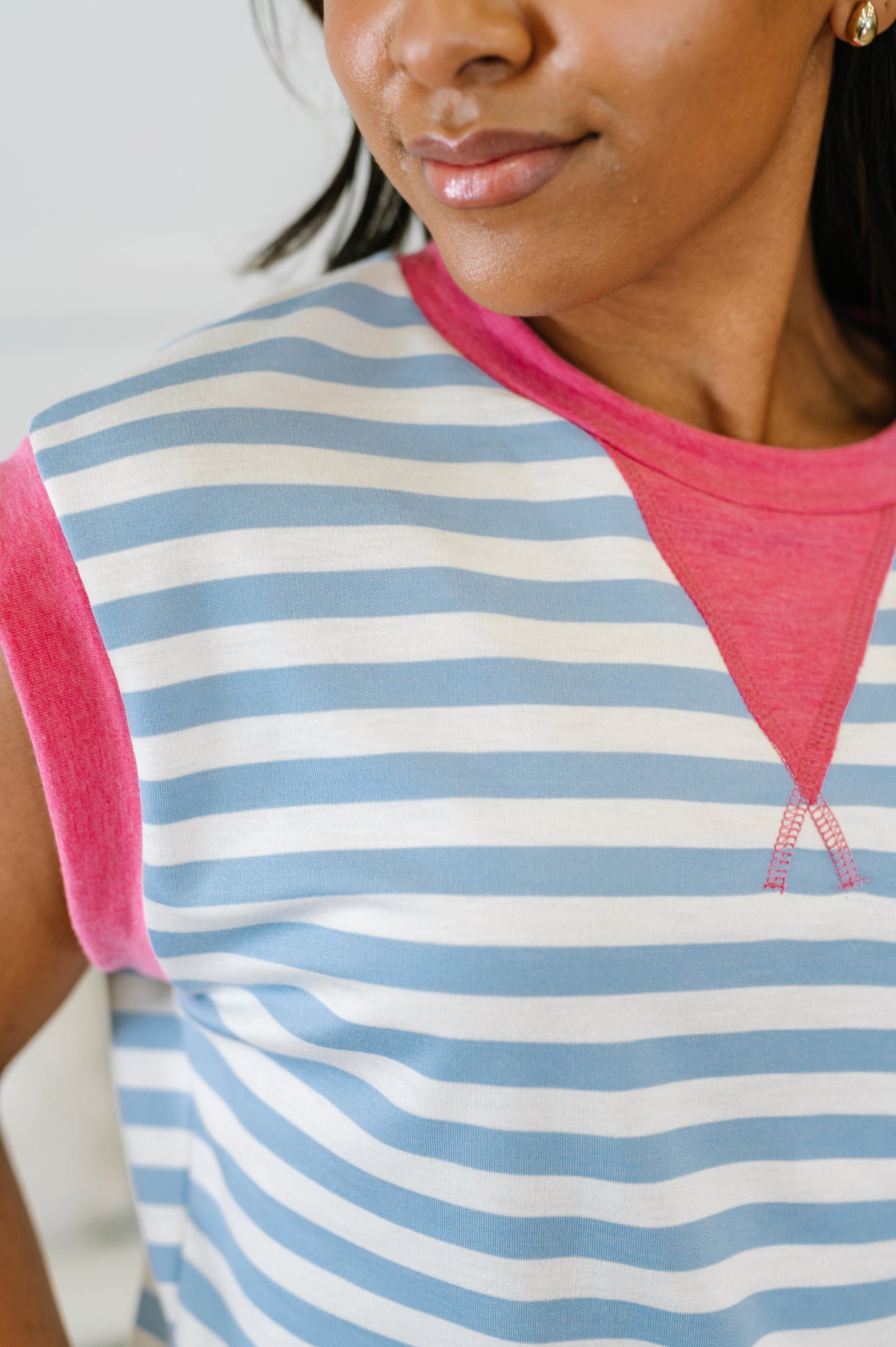 Woman wearing a striped shirt with pink sleeves and neckline.