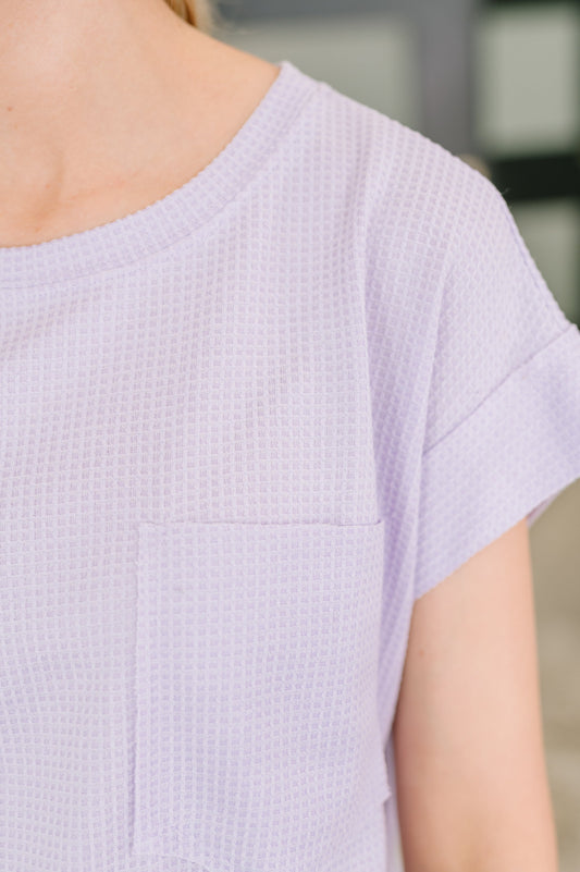 Close-up of a person wearing a light purple textured dress with a blurred background